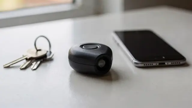 Taschenalarm-Sirene auf einem Tisch neben Schlüsselbund und Smartphone