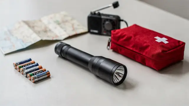 Taschenlampe in der Notfallausrüstung mit Batterien und geordnetem Zubehör