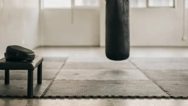 Selbstverteidigung trainieren in einer Trainingshalle mit Boxsack und Matten