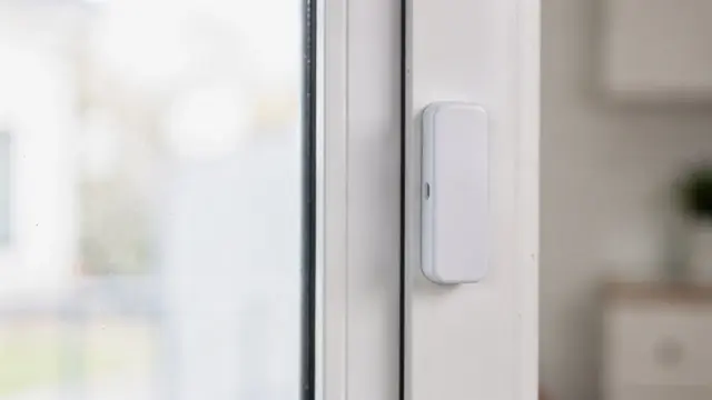 Fensterkontakt-Alarm an einem weißen Fensterrahmen als Teil des Einbruchschutzes