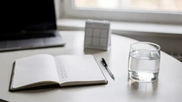 Ruhiger Schreibtisch mit Notizbuch und Kalender zum Thema Stress kontrollieren